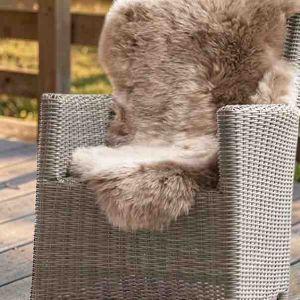 Taupe sheepskin rug on a rattan patio chair