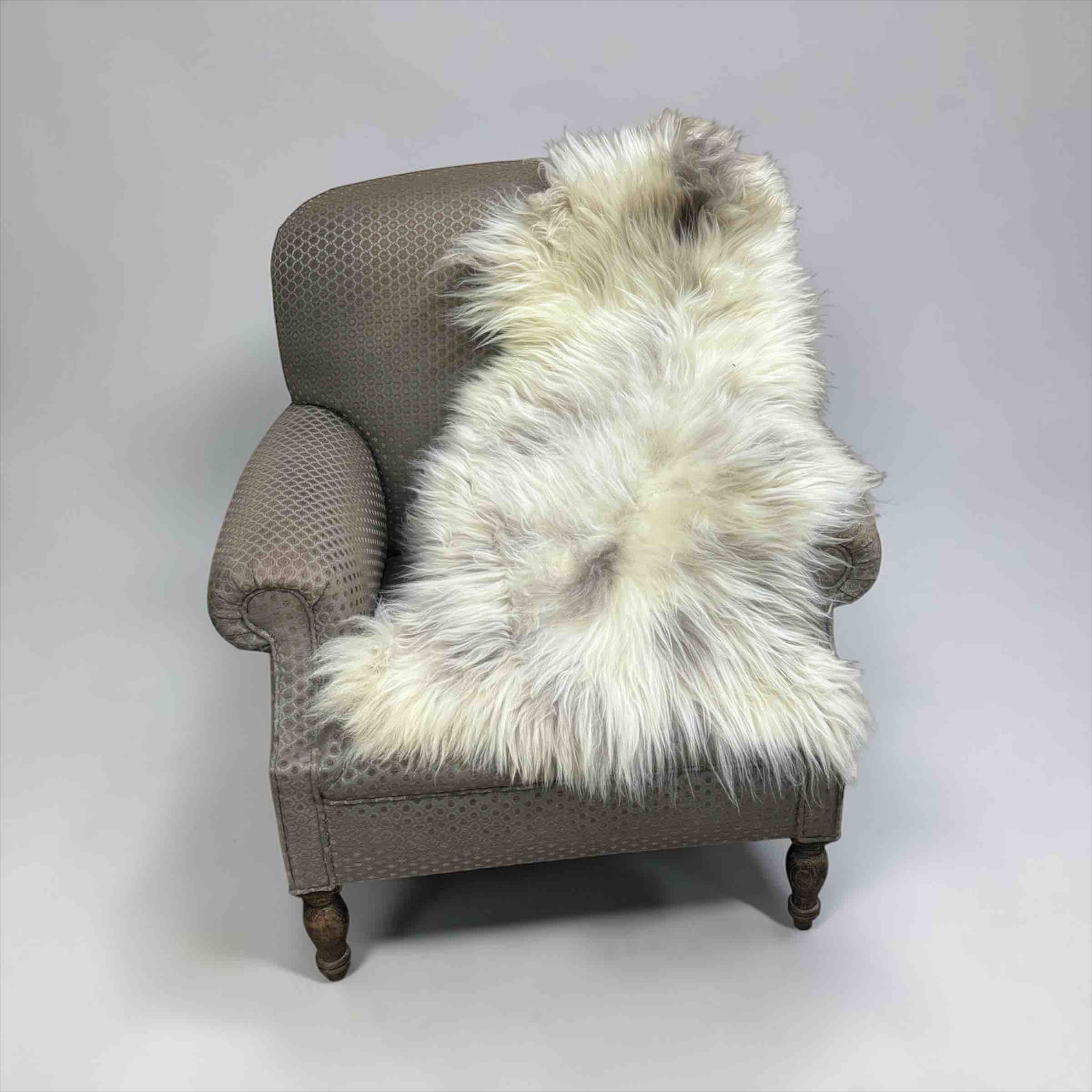 Gray armchair with a white fur throw on a plain background