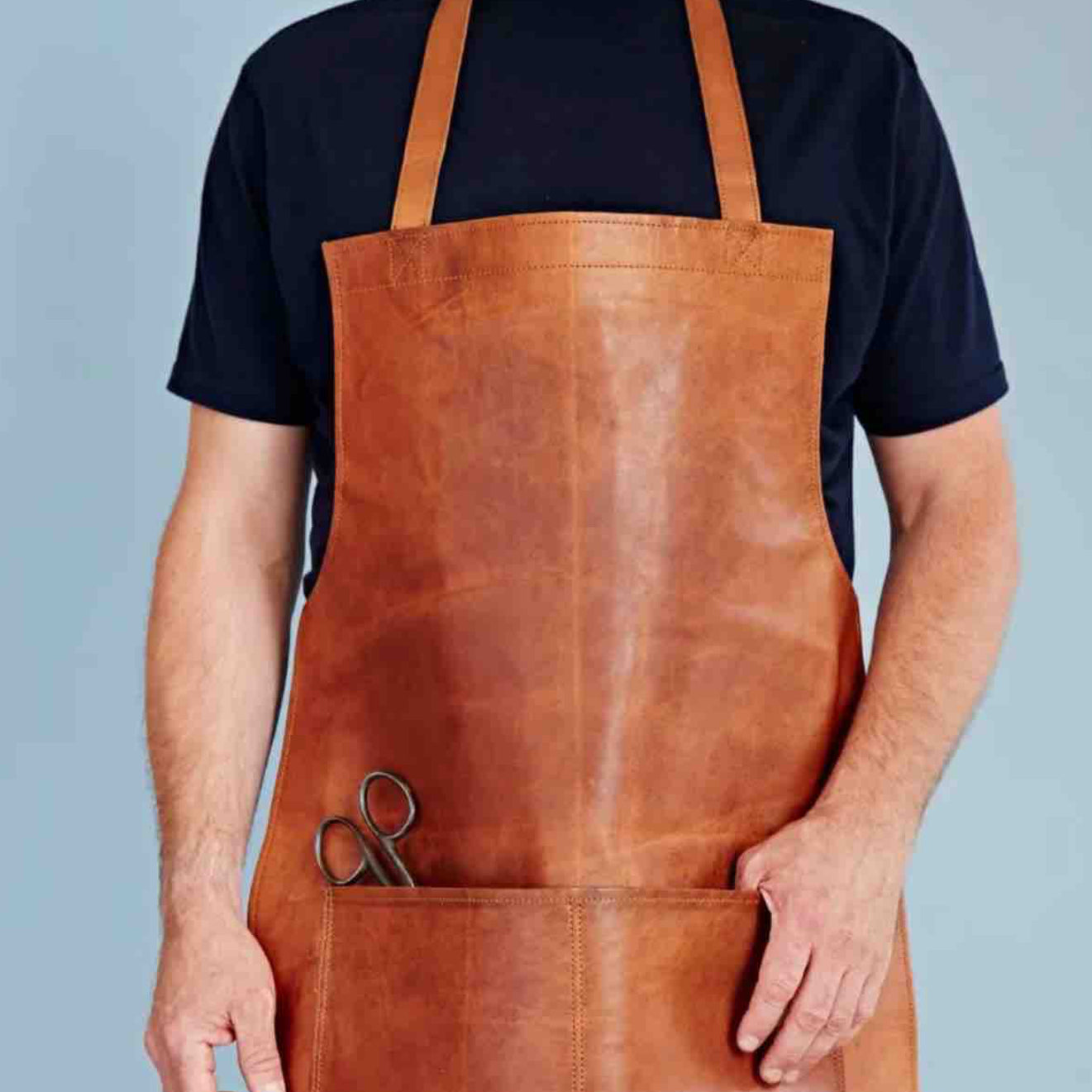 Person wearing a brown leather apron with a blue background
