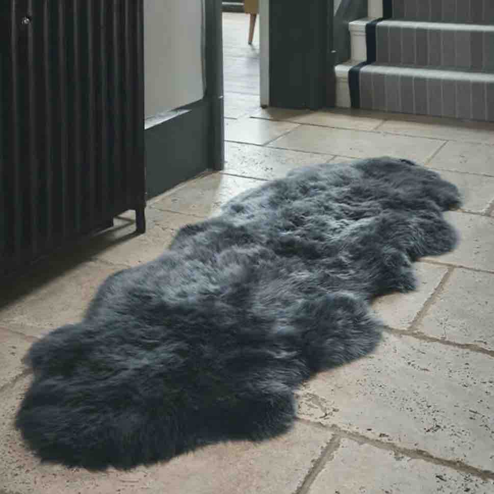 Long, dark gray sheepskin rug on a stone patio