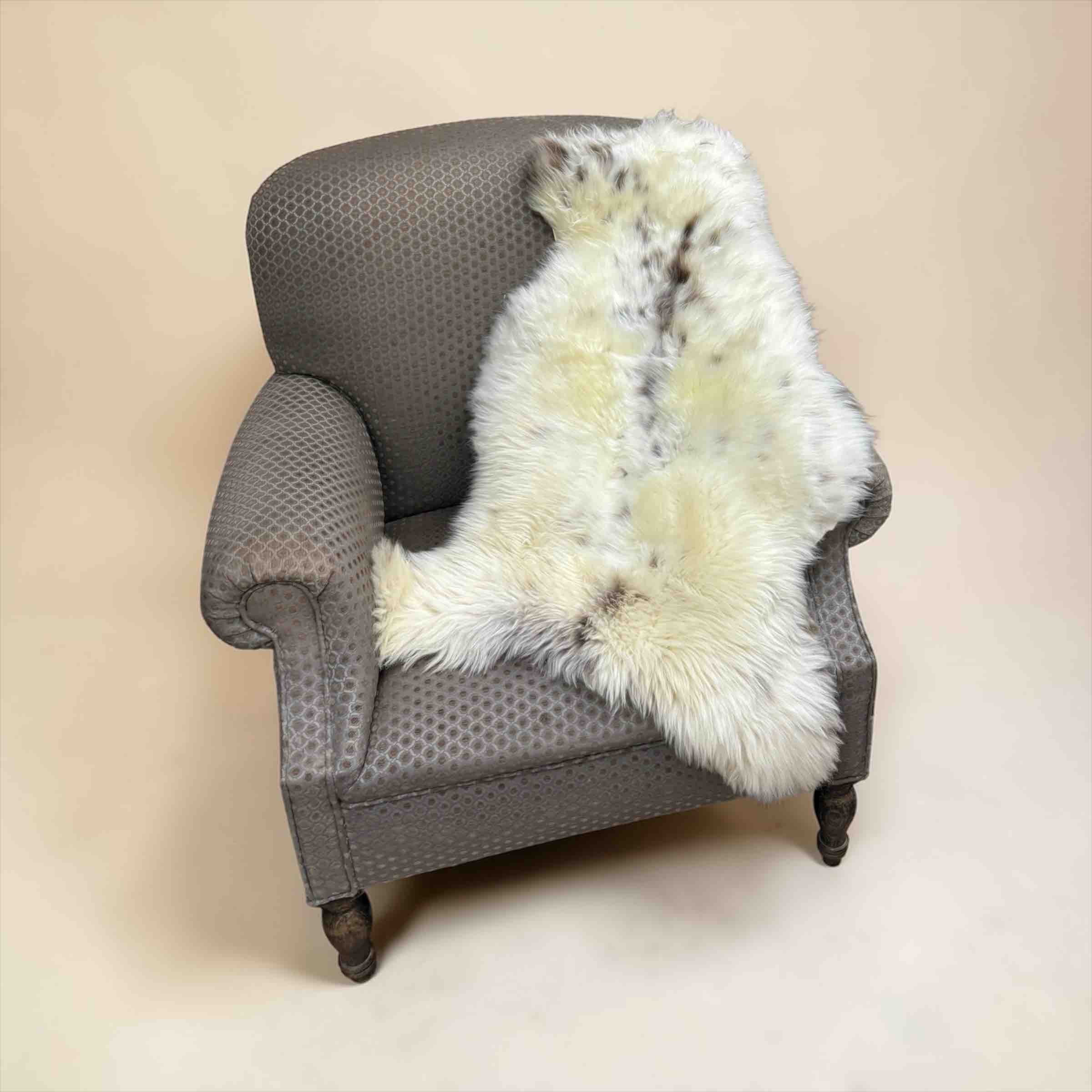 Gray armchair with a white fur throw on a beige background