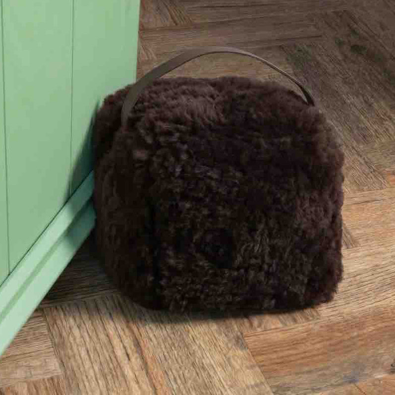 Brown fur bag on a wooden floor next to a green cabinet