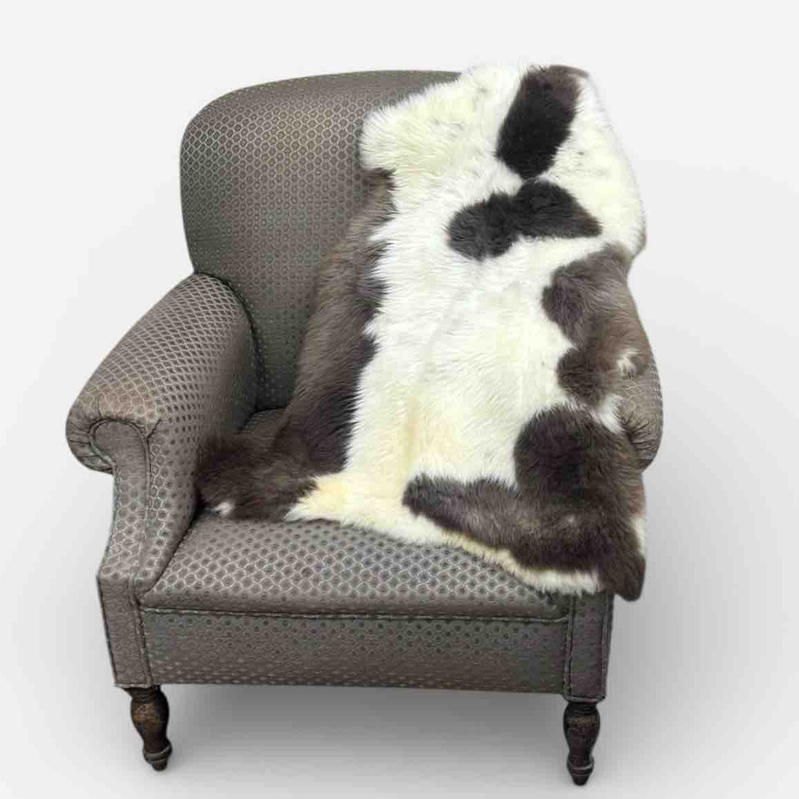 Gray armchair with a sheepskin rug draped over it on a white background