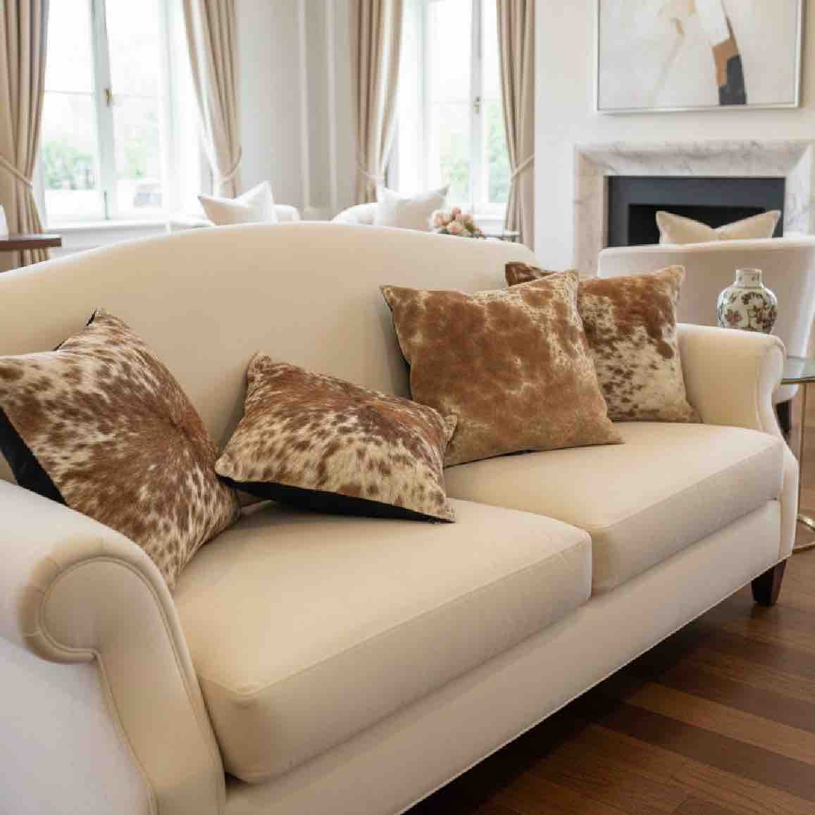 Beige sofa with cowhide patterned cushions in a living room setting.