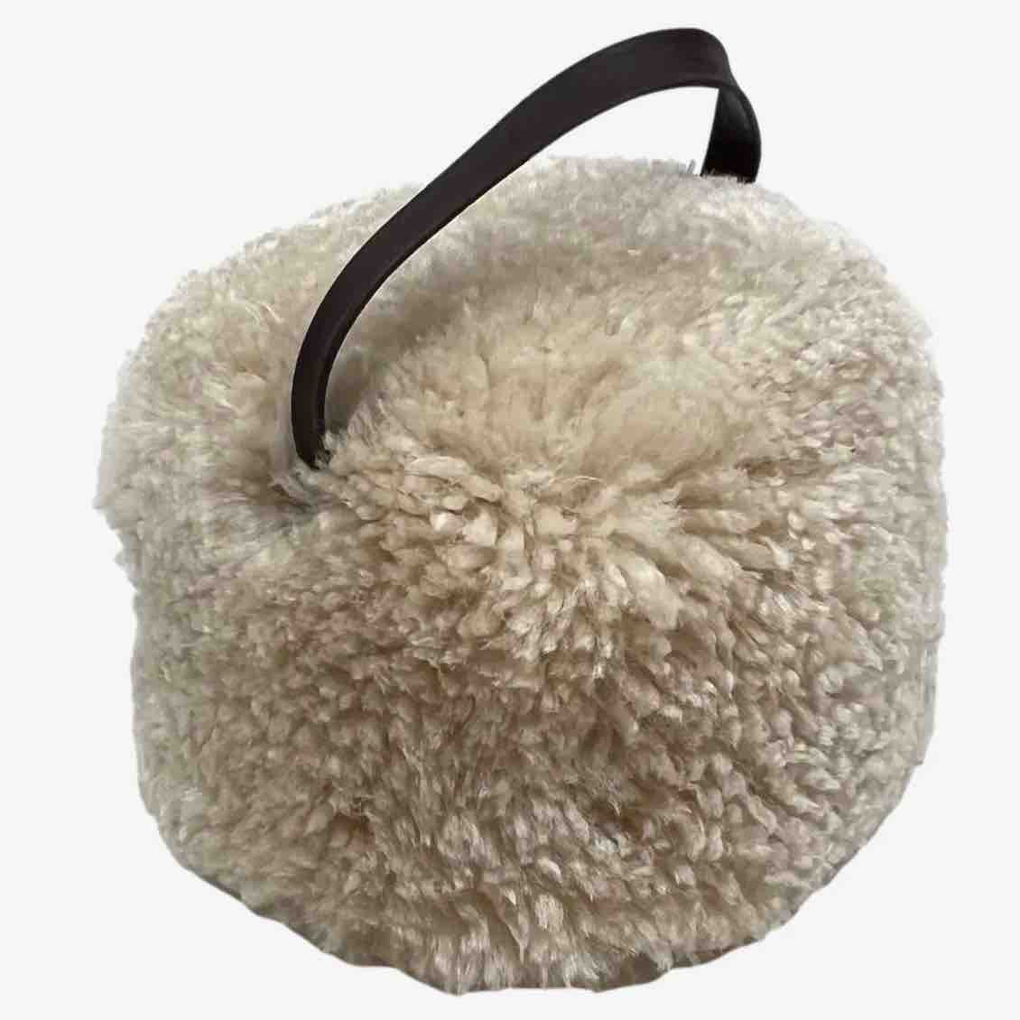 Beige fluffy bag with a black handle on a white background