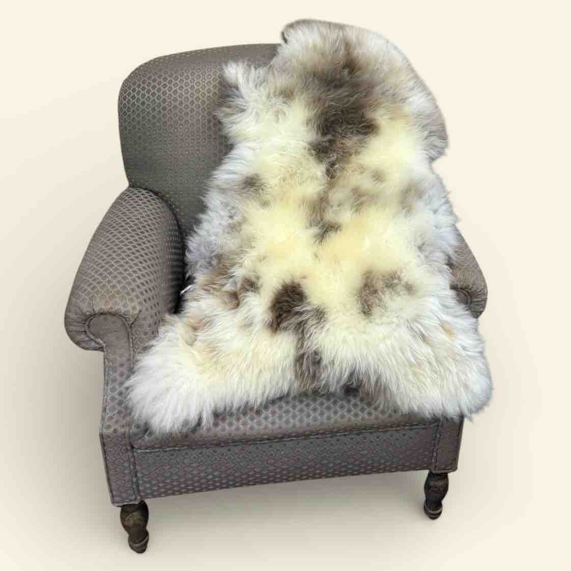 Gray armchair with a fur throw draped over it on a plain background