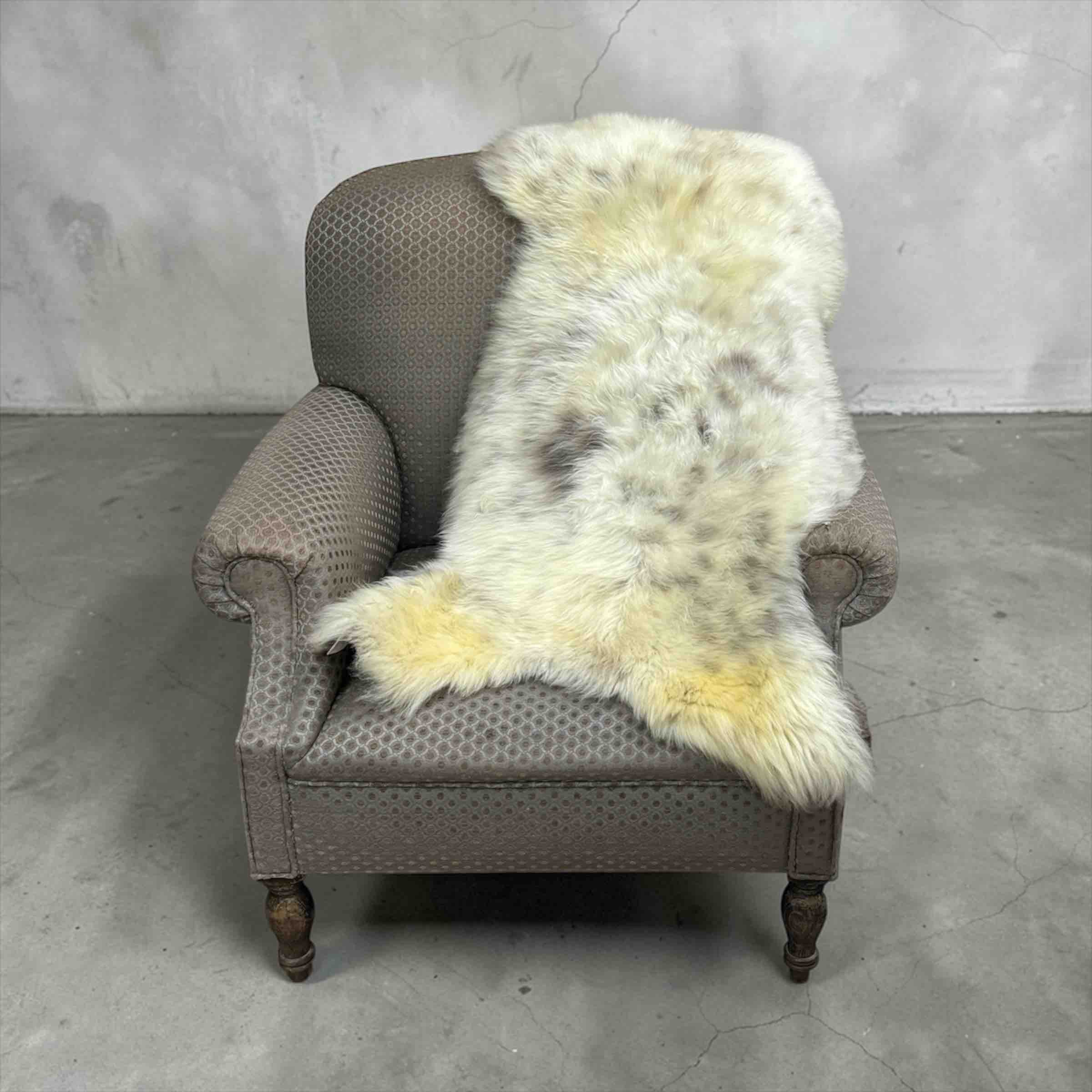 Gray armchair with a white fur throw on a concrete floor and gray wall background