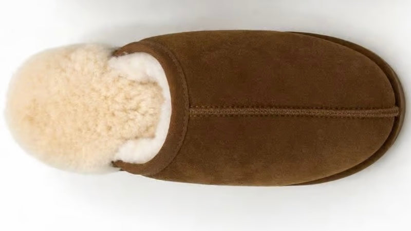 A single brown suede slipper with a fluffy cream shearling lining, shown from a top-down view on a white background.
