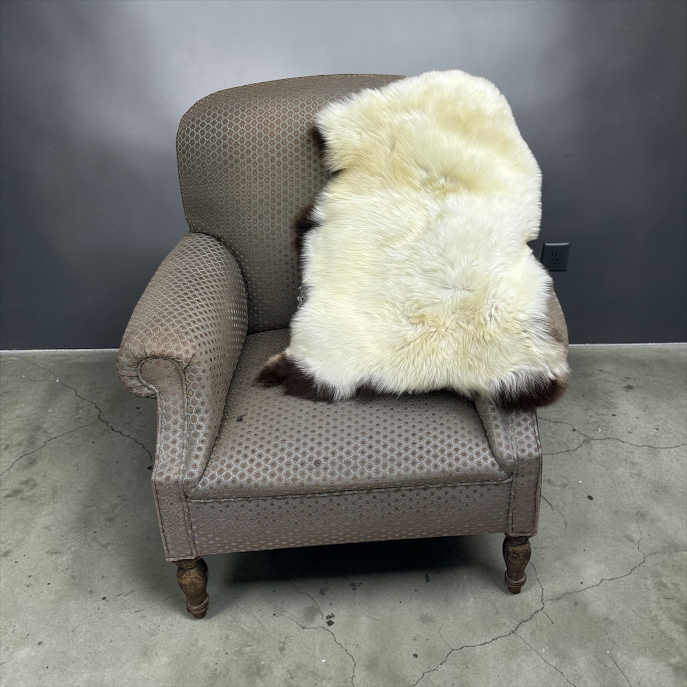 Gray armchair with a white fur throw on a gray floor and background