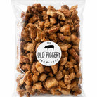 A clear plastic resealable bag filled with small browned snack pieces, featuring a round white label that reads 'The Old Piggery Farm Shop' with a black pig silhouette, on a white background.