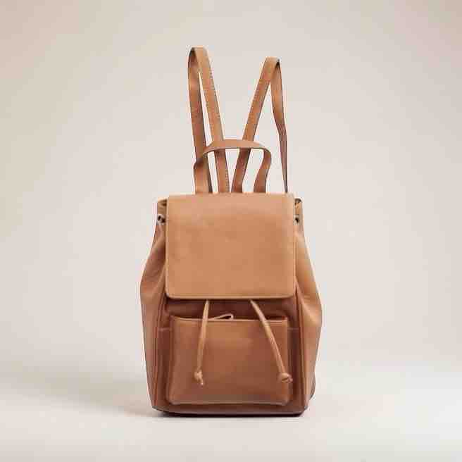 Brown leather backpack on a light beige background