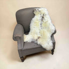 Gray armchair with a white fur throw on a beige background