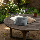 Three fur pillows in white, gray, and brown on a wooden deck.