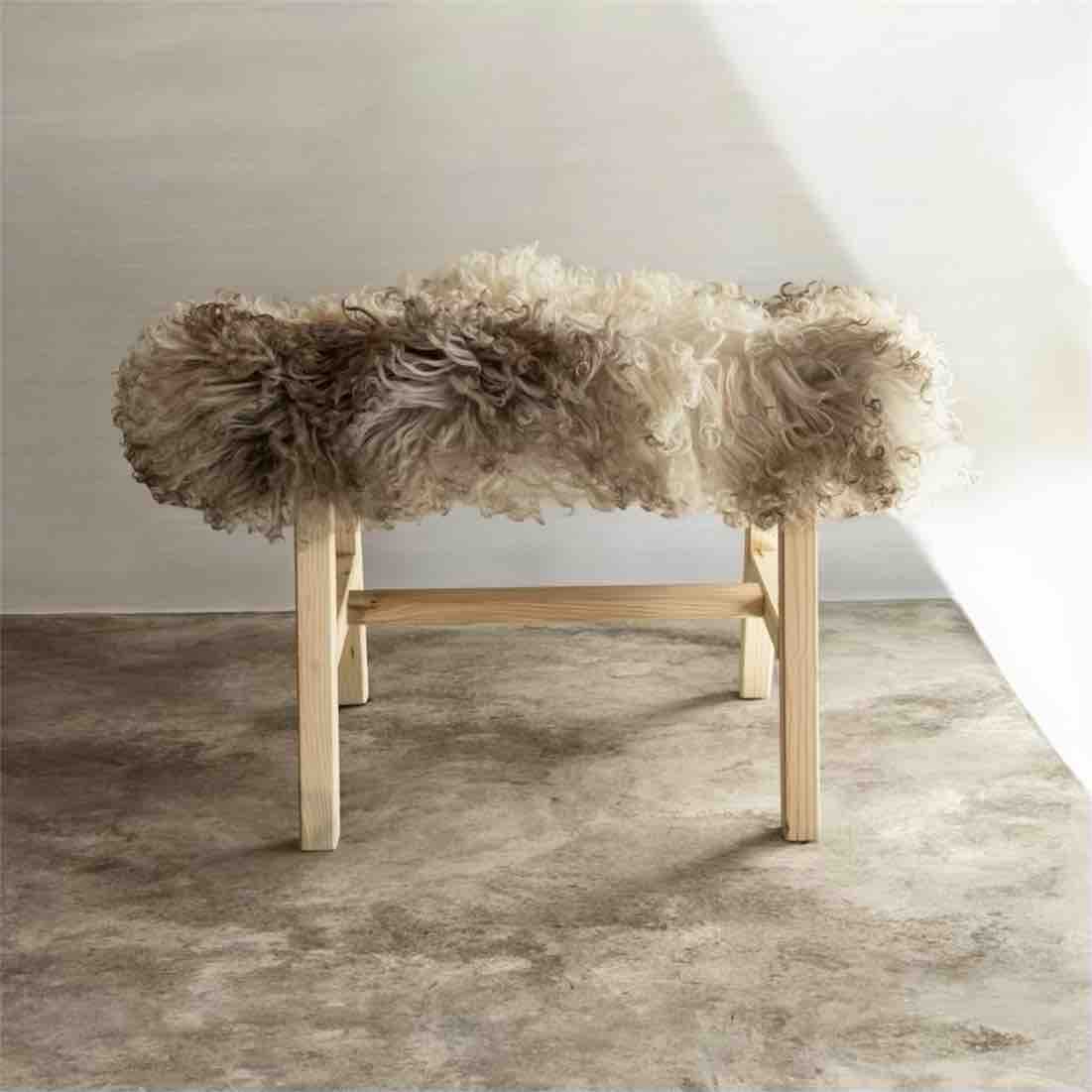 Wooden stool with fluffy fur cover on a neutral background