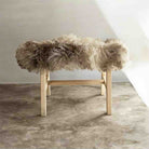 Wooden stool with fluffy fur cover on a neutral background