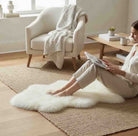 Woman sitting on a white fur rug in a cozy living room.
