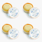 Four round soap bars in their packaging with decorative labels on a white background