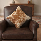 Brown and white cowhide pillow on a gray sofa