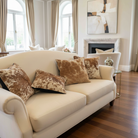 Beige sofa with cowhide patterned cushions in a living room setting.