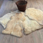 Four light brown fur rugs on a wooden floor with a wicker basket.
