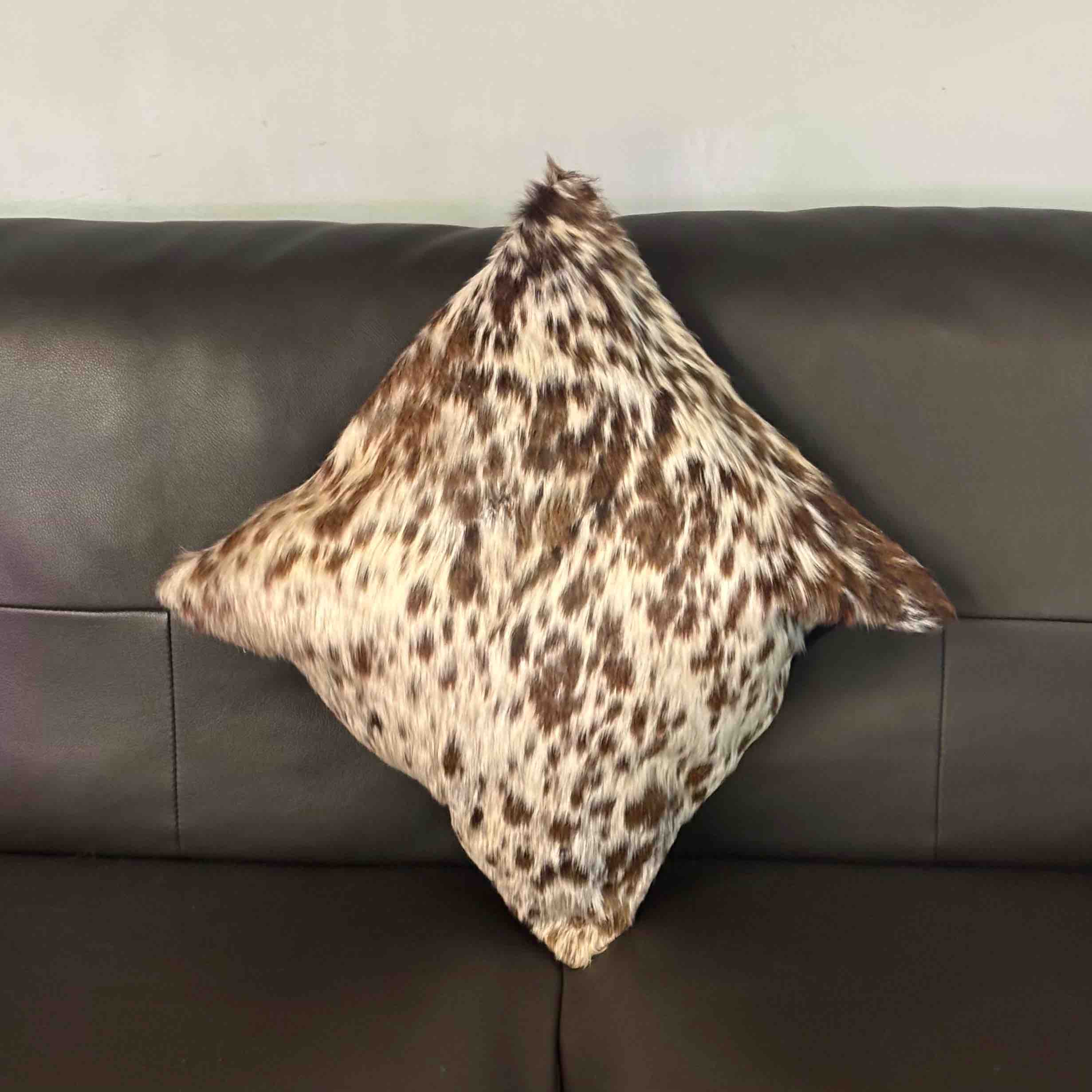 Spotted pillow on a gray sofa against a neutral wall