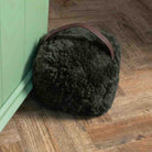 Sheepskin ear muffs on a wooden floor next to a green cabinet.
