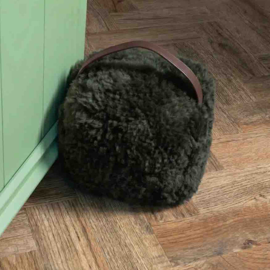 Sheepskin ear muffs on a wooden floor next to a green cabinet.