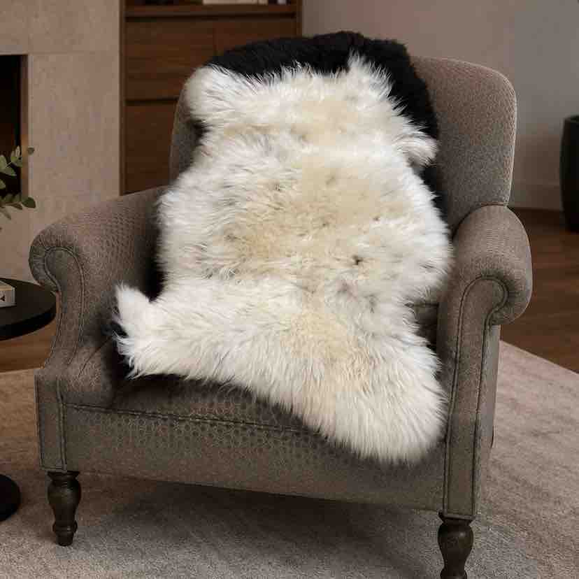 Gray armchair with a white and black fur throw in a living room setting.