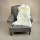 Gray armchair with a white fur throw on a beige background