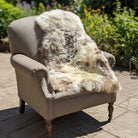 Gray armchair with a fur throw in a room with furniture and boxes.