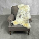 Gray armchair with a white fur throw on a concrete floor and gray wall background