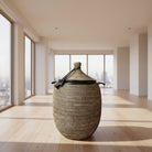 Woven basket with a lid on a wooden floor next to a plant