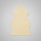 A beige shaggy rug with an irregular, organic silhouette, shown against a plain white background with a small product tag attached.