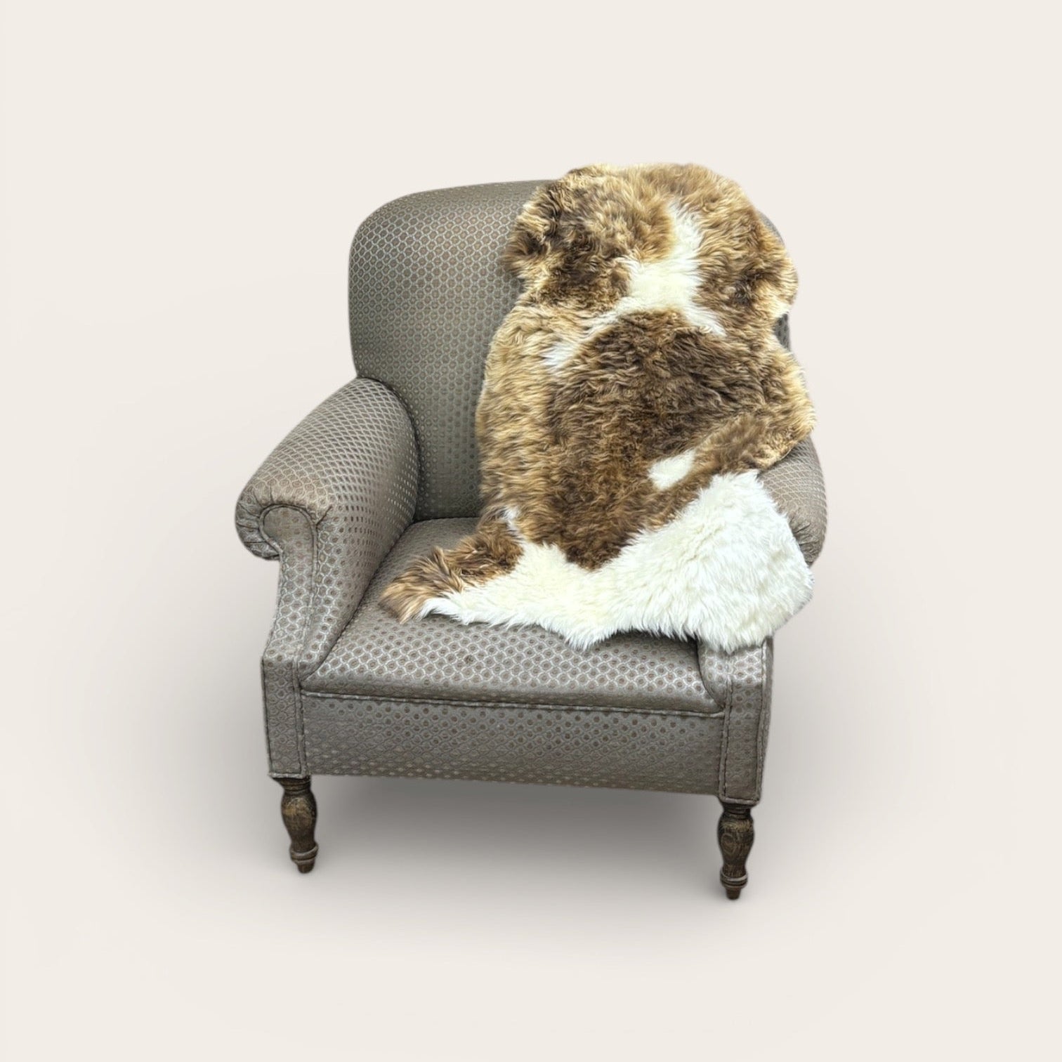 Gray armchair with a brown and white fur throw blanket on a light gray background