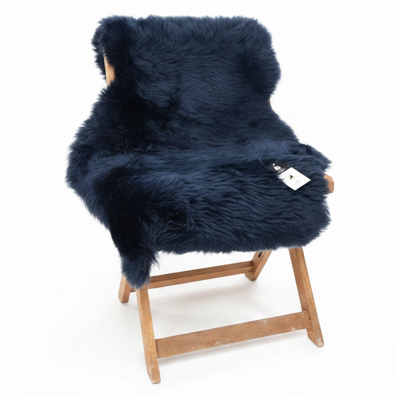 A large sheepskin rug in white, placed on a chair with a fireplace in the background.
